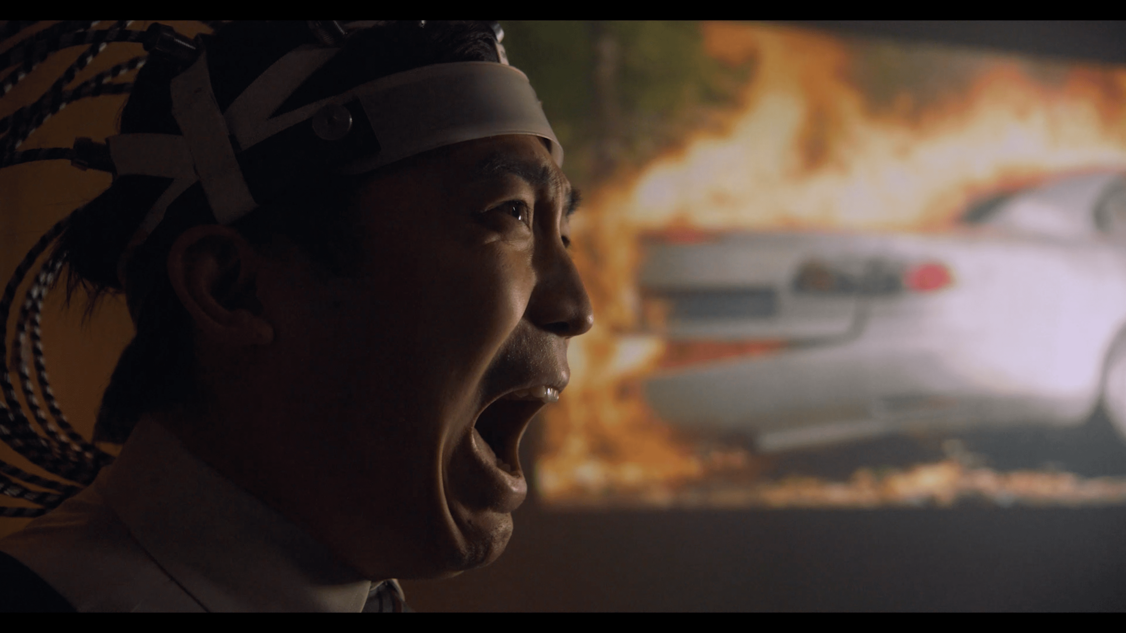 Man yelling with burning car in background from the film "Ouch!"