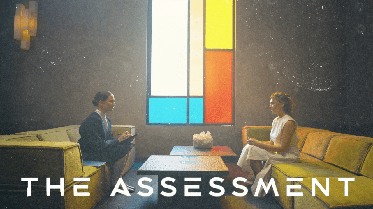 The Assessment Film Review Thumbnail with Alicia Vikander and Elizabeth Olsen sitting opposite each other