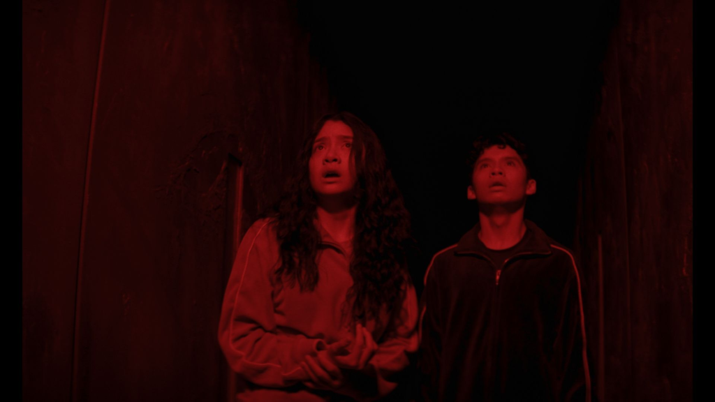 Emma Ho and Ian Ho doused in red light in the film Home Bodies