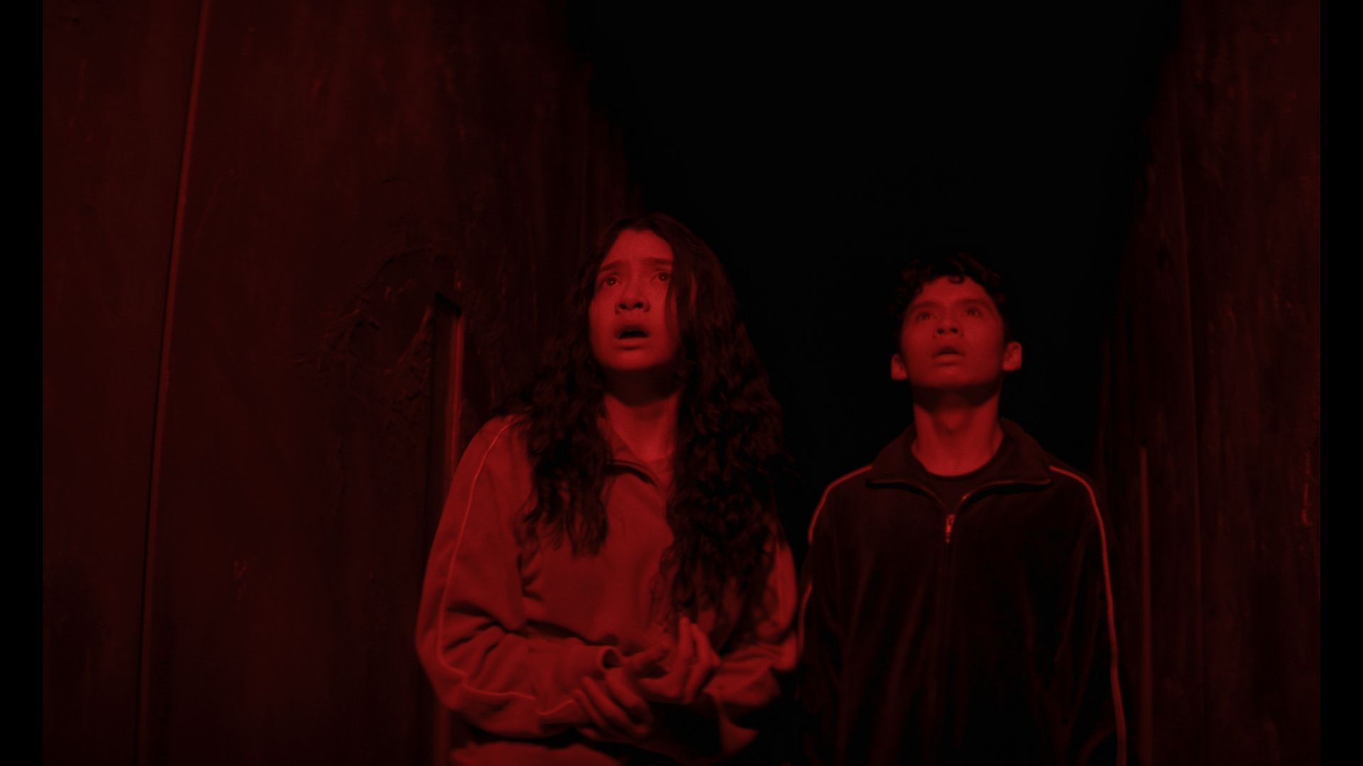 Emma Ho and Ian Ho doused in red light in the film Home Bodies