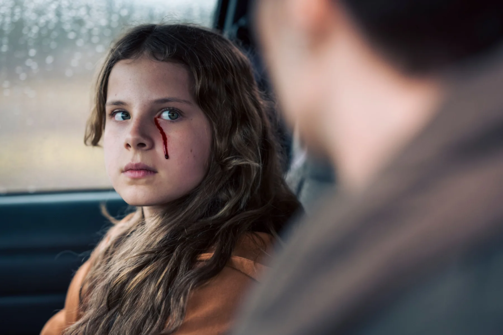 Young girl with blood below her eye sitting in a car in Freaks Part II