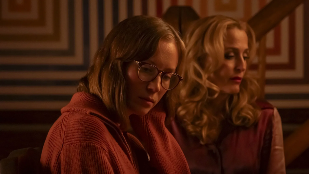 Two women sitting in warm low light in Teenage Sex and Death at Camp Miasma