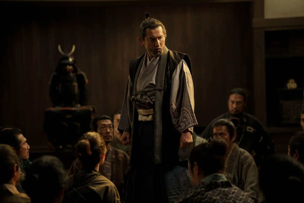 Samurai standing before a seated group in The Samurai and the Prisoner