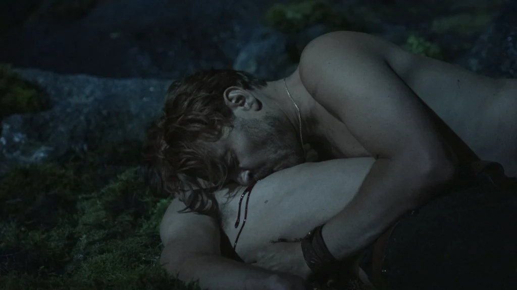 Pilou Asbæk as Helge drinks blood from Egor Venned as Baldur on wet rocks in No Rest for the Wicked