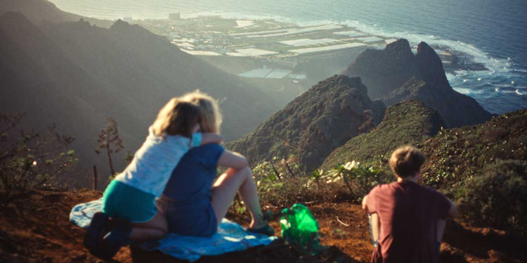 Melli hugs her mother, Ella, on a mountainside overlooking the Tenerife coastline, while Lux sits to their right in Everytime.