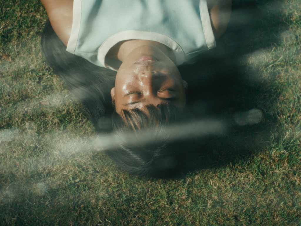 Young woman lies on grass with her eyes closed in Filipiñana